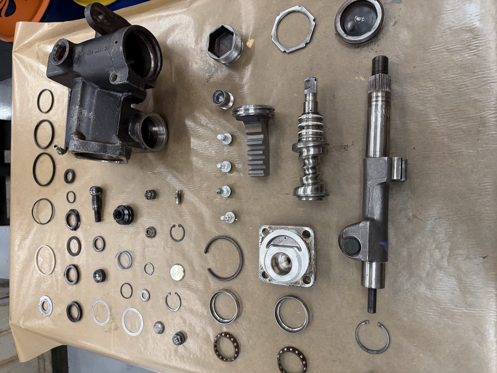 Every internal component of the 1988 Adwest steering box laid out: housing, shafts, piston, valve, bearings, seals and clips